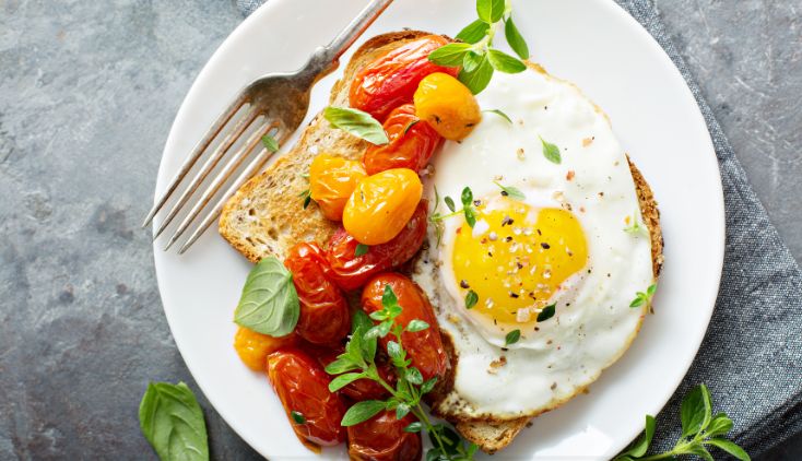 A sunny side up egg on a plate with fresh tomatoes.