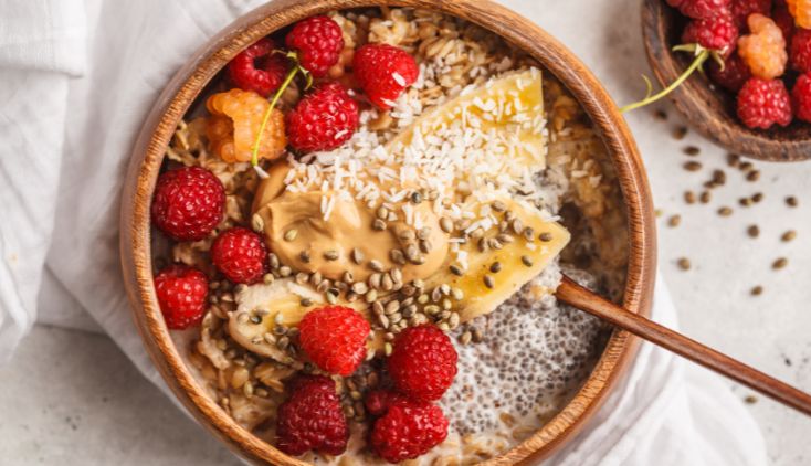 A bowl of oatmeal with raspberries, peanut butter and chia seeds in it.