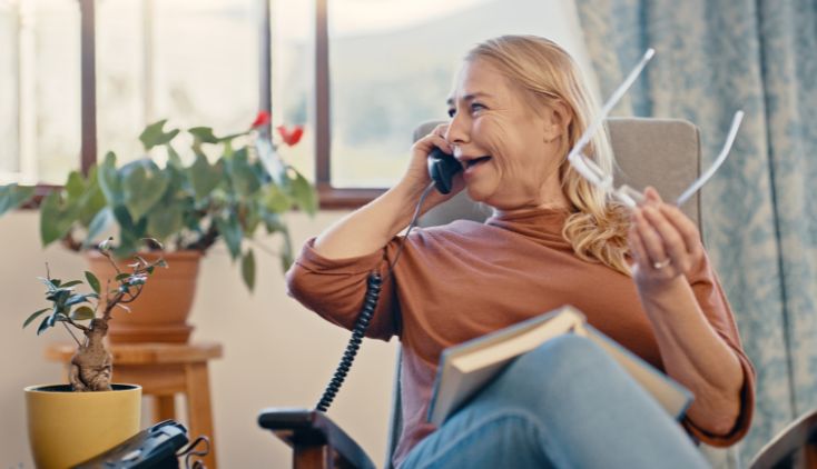 An older woman sitting in a chair, talking on the phone.